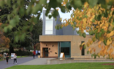 Image of Seattle University Chapel (St. Ignatius) with foliage surrounding. A few people pictured moving around the chapel.