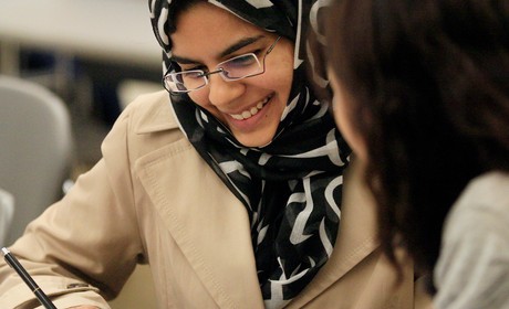 Two women in hijab studying in a classroom.