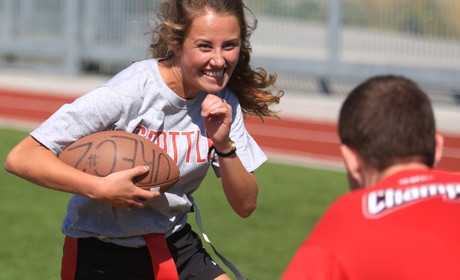 A girl is running with a football on a field.