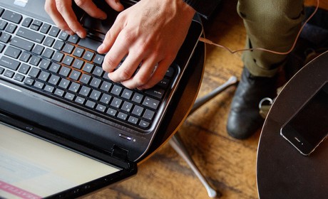 Hands type on a laptop