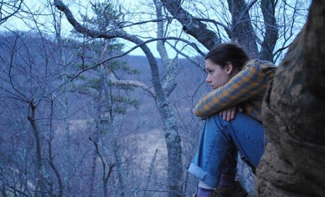 Student sitting on a mountain with tree branches
