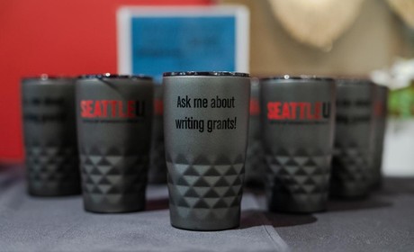 Coffee mugs with the text “Ask me about writing grants!”