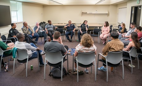 Participants and Seattle police officers sit in a circle during a Micro Community Policing discussion.