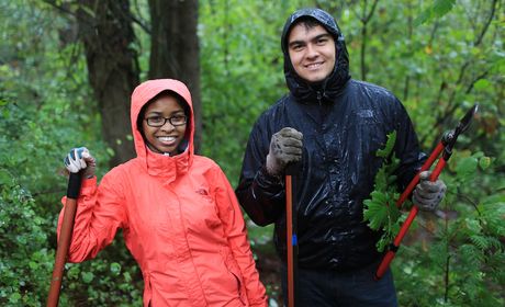 Two people in the rain doing community service