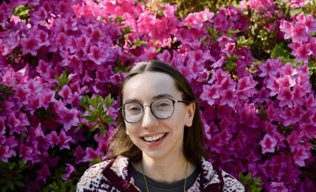 Upperbody headshot of Sophia Hampton with pink flowers in the background
