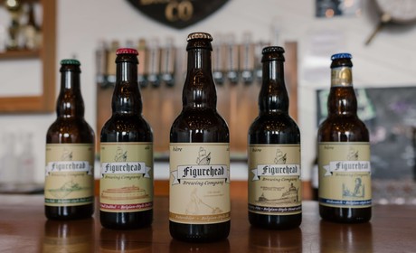 Five beer bottles in a row with Figurehead Brewing labels