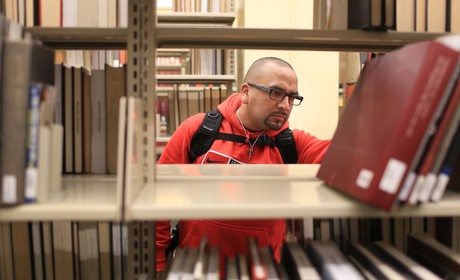 Student looking at books on library shelf