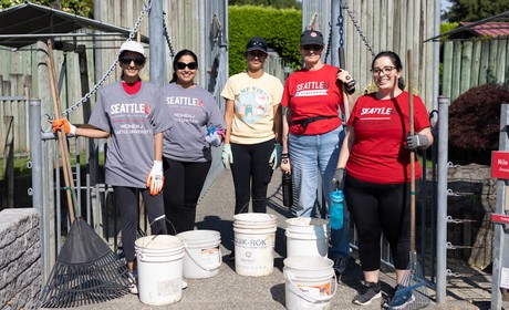 Five members of Women of SU holding rakes and buckets at a volunteer event.