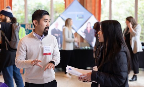Alumni employer speaking with a student at a career fair