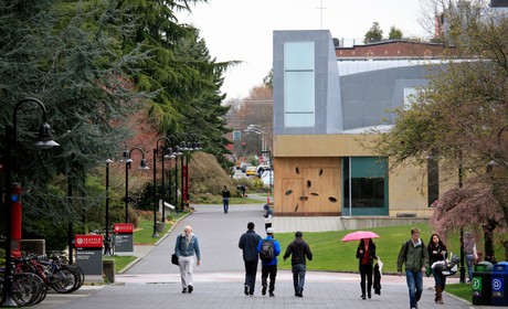 A group of people walking down a sidewalk in front of a building.