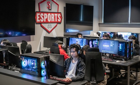 A group of people sitting at desks in an esports room.