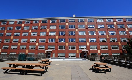 A large red brick building with benches and picnic tables.