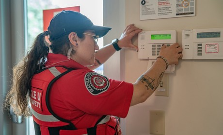 DPS officer pushing buttons on an alarm panel.