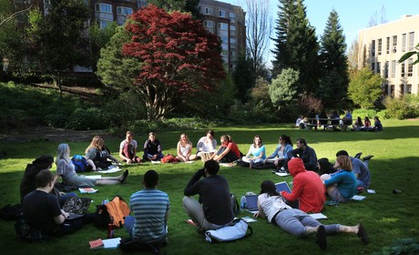 A group of people sitting on grass in a park.