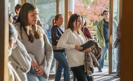 Students and parents stand listening to a presentation