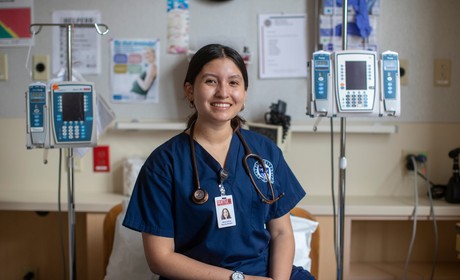 A nurse sitting in a hospital bed with two iv pumps.