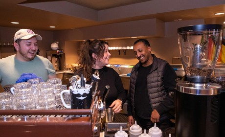 A group of people standing behind a counter in a coffee shop.