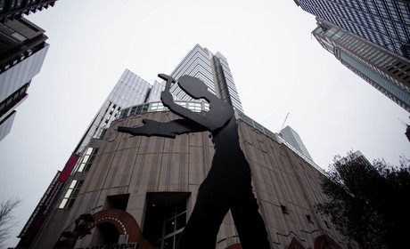 A statue of a man in front of tall buildings.