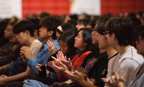 Audience members clapping at an event.