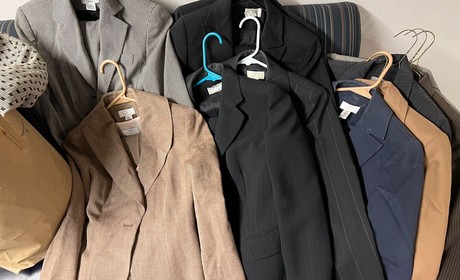 A selection of jackets and blazers hanging on a rack.