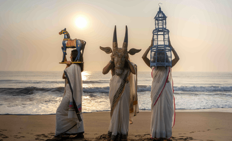 Three dancers with masks on beach