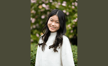 Upperbody headshot of Kelli standing in front of flowers and greenery