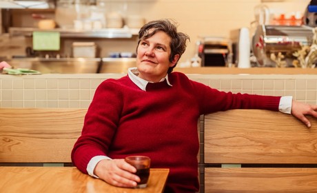 Alumnus Jody Hall sitting at a table with cup of coffee