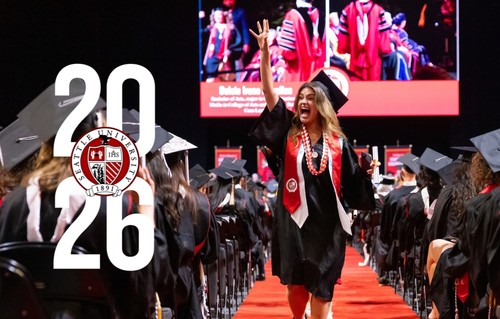 A graduating student waving during the graduation ceremony