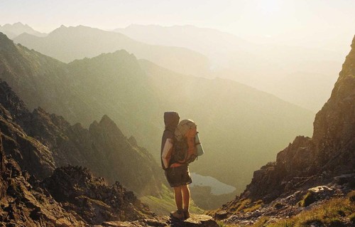 Hiker standing in front of mountains in fog