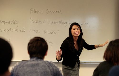 A woman gesturing in front of a class