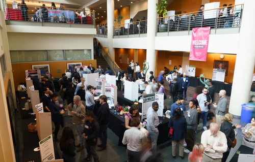 Students dressed in professional attire in large atrium space for poster session at Projects Day