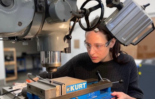 Female mechanical engineering student using a drill press