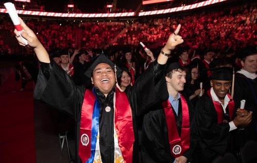 A student celebrating with raised peace signs