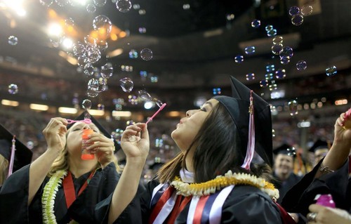 Graduating students blowing bubbles