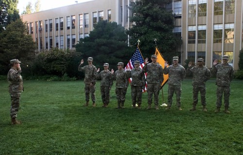 Cadets on green fatigues w/ hand raised outside