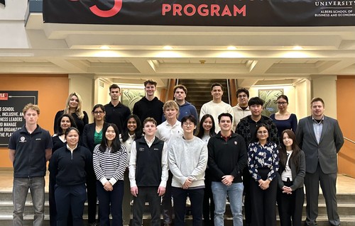 A group of students posing against a staircase with a banner above saying 35 Years of the Mentor Program