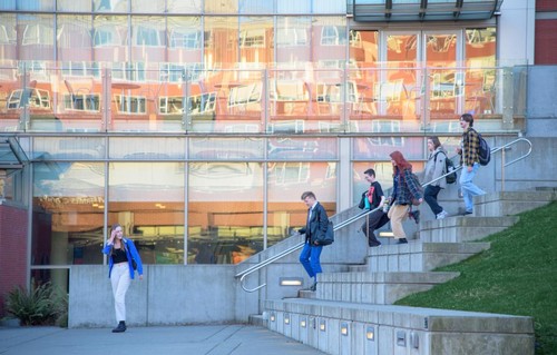 A group of people walking down steps in front of a building.