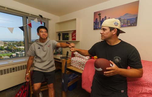 2 students in a resident room fist bumping