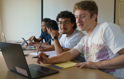 4 students looking at laptops