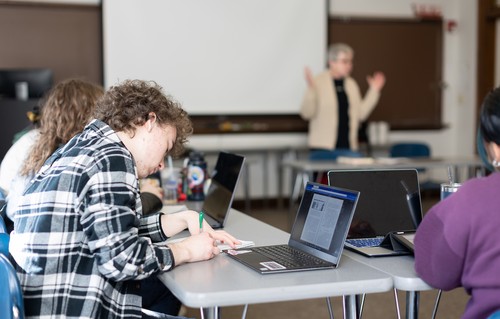 Honors students in class with faculty member in background