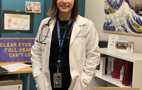 Naomi Diggs profile picture wearing her doctor's coat in her office with a bookshelf in the background