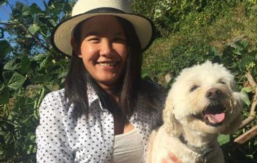 A portrait of Elly Hein Trinh holding a white fluffy dog