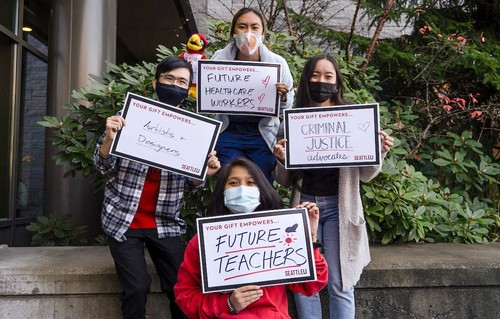 four students standing and holding signs of gratitude