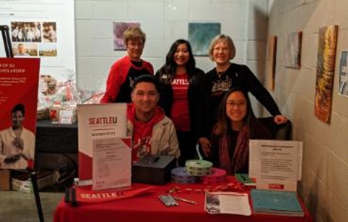 A group of five women sitting behind a check-in table at a Women of SU Fundraising event