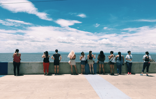 people by a sea wall facing the ocean