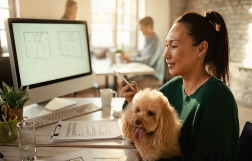 Woman with dog sitting in front of a computer monitor