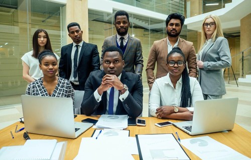 A group of people standing and sitting behind a desk.