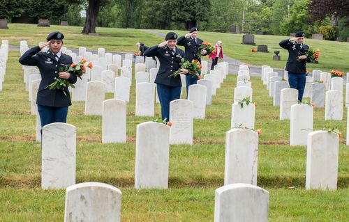 Cadets salute while placing flowers in cemetery for Memorial Day