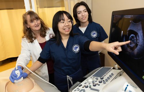 Two students and a professor operating an ultrasound machine