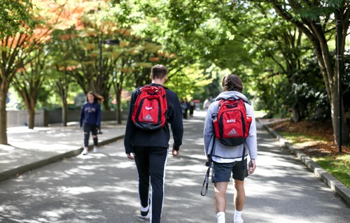 A group of people walking down a street with backpacks.